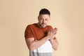 Greedy man rubbing hands on beige background