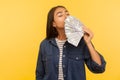 Greedy for money. Portrait of avaricious rich girl in denim shirt smelling earned dollar banknotes, enjoying success Royalty Free Stock Photo