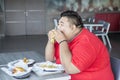 Greedy obese man eating fast foods in restaurant