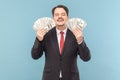 Greedy smiling man with mustache standing with closed eyes, holding dollar banknotes in hands. Royalty Free Stock Photo