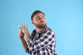 Greedy young man hiding money on light blue background