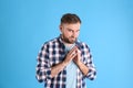 Greedy young man rubbing hands on light blue background