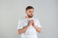 Greedy young man rubbing hands on light grey background