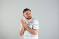 Greedy young man rubbing hands on light grey background