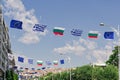 Greek, Bulgarian, and European Union flags waving above a street during the 87th TIF International Fair in Thessaloniki, Greece.