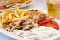 Greek chicken gyros with fries, salad, onions, tomatoes, tzatziki and a glass of beer
