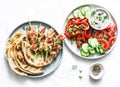 Greek chicken skewers, flatbread, tomatoes, cucumber salad, baked sweet pepper, tzatziki yogurt herb sauce on a light background, Royalty Free Stock Photo