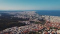 Greek city seen from aerial drone perspective. Typical Greek orange rooftops and whitewashed walls. Seashore.