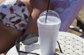 Greek frappe in cup with foam and body part of woman