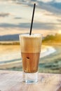 A greek cold coffee, freddo cappuccino placed on a wooden table over a beach background. Royalty Free Stock Photo