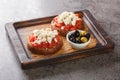 Greek dakos appetizer with barley rusk, tomatoes, feta cheese, oregano and olive oil closeup on the wooden board. Horizontal