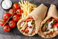 Greek fast food gyros with chicken, tomatoes, cucumbers and onions served with tzatziki sauce and french fries close-up on a board Royalty Free Stock Photo