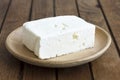 Greek feta cheese block on rustic plate and table. Royalty Free Stock Photo