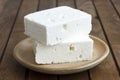 Greek feta cheese block on rustic plate and table.