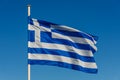 Greek flag on pole waving over blue background Royalty Free Stock Photo