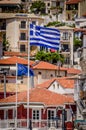 Greek Flag Waving Over Picturesque Coastal Town of Parga, Greece. European Union Flag and Traditional House Rooftops Royalty Free Stock Photo