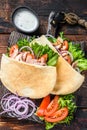 Greek gyros wrapped in pita breads with vegetables and sauce. Dark wooden background. Top view Royalty Free Stock Photo