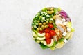 Greek inspired salad with grilled chicken meat, vegetables and feta cheese in a bowl on a table, with olive oil dressing