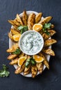 Greek lemon baked potato and tzadziki sauce - delicious snack, appetizer, tapas on a dark background, top view