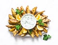 Greek lemon baked potato and tzadziki sauce - delicious snack, appetizer, tapas on a light background, top view