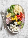 Greek lemon orzo salad. Feta, orzo, tomatoes, cucumbers, radishes, olives, peppers salad on a light background, top view. Healthy Royalty Free Stock Photo