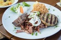 Greek mixed grill with grilled liver, Bifteki, Gyros, onions, tsatsiki, coleslaw and rice on wooden table Royalty Free Stock Photo