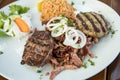 Greek mixed grill with grilled liver, Bifteki, Gyros, onions, Tsatsiki and rice on wooden table