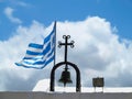 The Greek National flag near cross of small church against blue Royalty Free Stock Photo