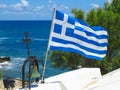 The Greek National flag near cross of small church against blue Royalty Free Stock Photo