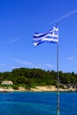 The Greek National Flag over seascape, beautiful turquoise sea , summer travel vacation. Royalty Free Stock Photo