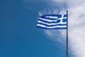 Greek national flag waving on the wind against blue sky and whit Royalty Free Stock Photo