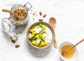 Greek natural yogurt with tropical fruits and granola on a light background, top view. Natural yogurt with kiwi, mango and