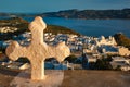 Christian cross and Plaka village on Milos island over red geranium flowers on sunset in Greece Royalty Free Stock Photo