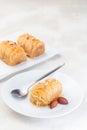 Greek pastry Kataifi with shredded filo dough stuffed with almond nuts, in honey syrup, on white plate, vertical, copy space