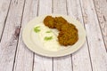 Greek plate of falafel balls with vegetables and sauce on white plate