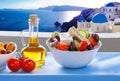 Greek salad against famous church in Oia village, Santorini island in Greece