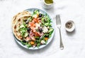 Greek salad with baked salmon on a light background, top view. Healthy mediterranean diet food