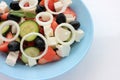 Greek salad in blue bowl on white background. Close-up of vegetable salad with fets cheese, black olives, cucumber and tomatoes. Royalty Free Stock Photo