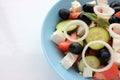 Greek salad in blue bowl on white background. Close-up of vegetable salad with fets cheese, black olives, cucumber and tomatoes. Royalty Free Stock Photo