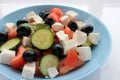 Greek salad in blue bowl on white background. Close-up of vegetable salad with fets cheese, black olives, cucumber and tomatoes. Royalty Free Stock Photo