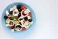 Greek salad in blue bowl on white background. Close-up of vegetable salad with fets cheese, black olives, cucumber and tomatoes. Royalty Free Stock Photo