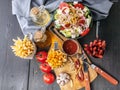 Greek salad with feta cheese, french fries, smoked sausages, tomatoes and garlic. Tasty food on a rustic background. Top view Royalty Free Stock Photo