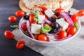 Greek salad with fresh cherry tomatoes, feta cheese, black olives, basil and onion on black wooden background Royalty Free Stock Photo