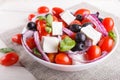 Greek salad with fresh cherry tomatoes, feta cheese, black olives, basil and onion on white wooden background Royalty Free Stock Photo