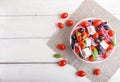 Greek salad with fresh cherry tomatoes, feta cheese, black olives, basil and onion on white wooden background Royalty Free Stock Photo