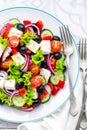 Greek salad of fresh cucumber, tomato, sweet pepper, lettuce, red onion, feta cheese and olives with olive oil Royalty Free Stock Photo