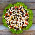 Greek salad of fresh cucumbers, tomatoes, sweet peppers, feta cheese and olives with olive oil framed by green leaves of lettuce o Royalty Free Stock Photo