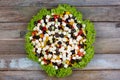 Greek salad of fresh cucumbers, tomatoes, sweet peppers, feta cheese and olives with olive oil framed by green leaves of lettuce o Royalty Free Stock Photo