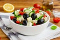 Greek salad of fresh juicy vegetables, feta cheese, herbs and olives in a white bowl on a wooden background. Healthy food. Royalty Free Stock Photo