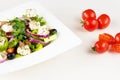 Greek salad with fresh tomato, cucumber, red onion, basil, feta cheese, black olives, Italian herbs and olive oil in white dish on Royalty Free Stock Photo